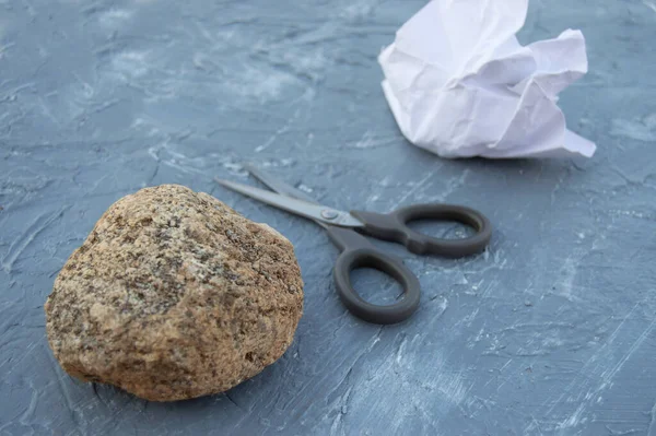 Taş, makas ve kağıt gri arka planda. Karar vermek için popüler bir yöntem. Bir çocuk oyununun özellikleri.
