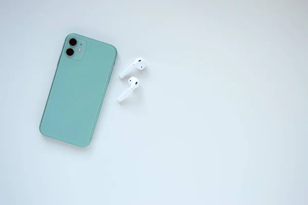 Ein Modernes Mintfarbenes Smartphone Mit Zwei Drahtlosen Kopfhörern Auf Weißem — Stockfoto