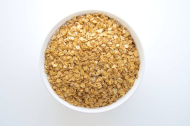 Beyaz arka planda beyaz bir kasede kuru yulaf ezmesi. Sağlıklı yiyecekler. Üst görünüm.