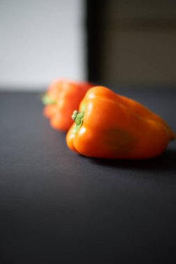 Bahçeden siyah arka planda üç taze portakal biberi..