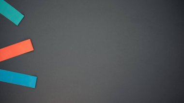 Siyah arka planda fitness için çok renkli elastik bantlar. Farklı renklerde, kırmızı, mavi ve turkuazda elastik bantlar. Evde eğitim için ideal. Metin için boşluk.