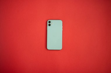 Parlak kırmızı arka planda, modern, nane renginde bir akıllı telefon. Modern ve minimalist kavram.