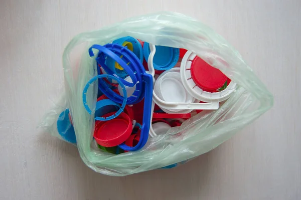 Lots of colorful plastic caps and rings in plastic bag. No plastic surgery. Conscious consumption and recycling of plastic waste. Sorting garbage.