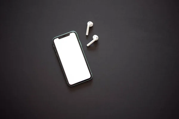 现代智能手机 白色屏幕和两个黑色背景的白色无线耳机 现代和简约的概念 — 图库照片