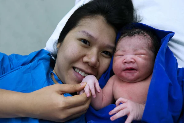 Anne dokunmatik küçük el onun Doğum, hastane yatak doğumhaneye, üzerinde Asya kız bebek