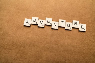 Londra, İngiltere - 24 Mayıs 2019: The Word Adventure, kahverengi dokulu arka plan üzerinde ahşap harf karoları ile yazılmış