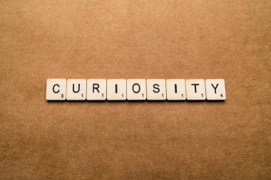 Londra, İngiltere - 24 Mayıs 2019: Kelime Curiosity, kahverengi dokulu arka plan üzerinde ahşap harf karoları ile yazılmış