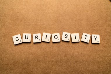 Londra, İngiltere - 24 Mayıs 2019: Kelime Curiosity, kahverengi dokulu arka plan üzerinde ahşap harf karoları ile yazılmış