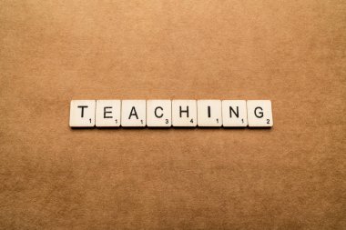 Londra, İngiltere - 24 Mayıs 2019: Öğretmen kelimesi, kahverengi dokulu bir arka plan üzerinde tahta harf karoları ile yazılmış