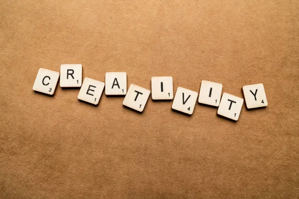 LONDON, UK - May 24 2019: The word CREATIVITY, spelt with wooden letter tiles over a brown textured background — Stock Photo, Image