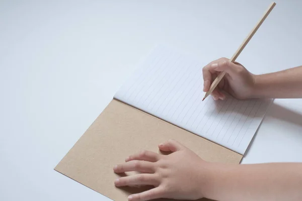 Childs elleri beyaz arka planda kalem ile açık bir defter sayfası tutun