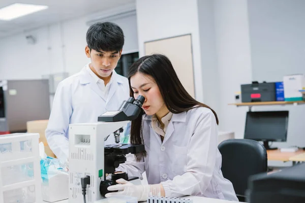 Two medical scientist working in Medical laboratory , young female scientist looking at microscope. select focus in young female scientist