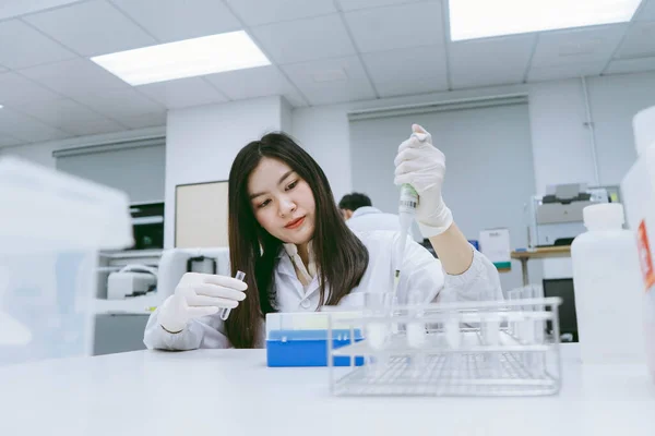 Young medical scientist working in medical laboratory , young female scientist using auto pipette to transfer sample