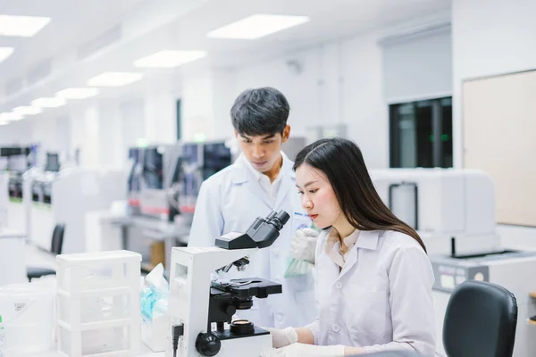 顕微鏡を見ている若い女性科学者です顕微鏡を見ている女性科学者です 若い女性科学者に焦点を当て — ストック写真