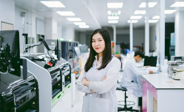 白衣を着た若い笑顔の科学者が医療研究所の自動血液分析器で立っています — ストック写真