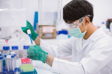 Genç bilim adamı, biyo-koruma dolabındaki PCR testi için mikro santrifüj tüpüne pipet transfer numunesi kullanıyor..