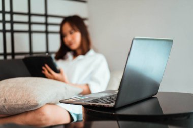 Oturma odasında otururken dizüstü bilgisayarda çalışan genç bir kadın. ev kavramından çalışma