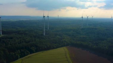 Almanya 'daki Berlichingen yakınlarındaki rüzgar türbinlerinin hava görüntüsü. Baharın ilerleyen saatlerinde bulutlu bir gökyüzüyle.
