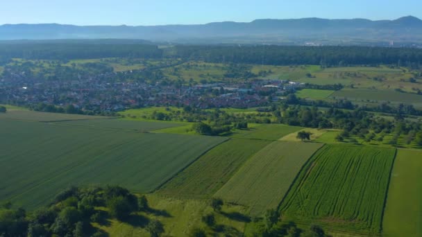 ドイツのホショドルフの空中 背後に山がある村を背景に 畑の上にカメラのパンが残っている — ストック動画