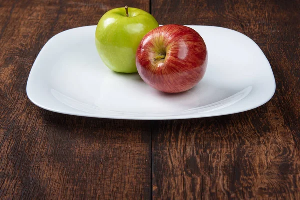Apple on a white plate on a rustic wooden surface with a black background. selective focus.