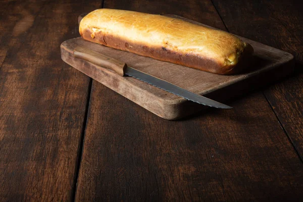 Homemade bread stuffed with shredded chicken on rustic wood and knife with black background, selective focus.
