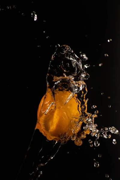 Orange with a beautiful splash of water with black background and selective focus.