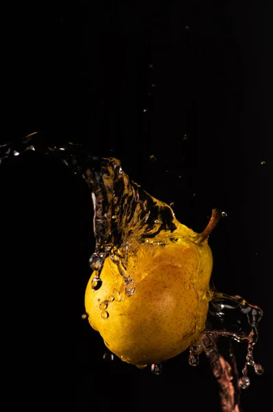 Pear with a beautiful splash of water with black background and selective focus.