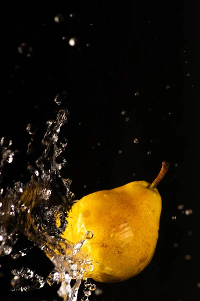 Pear with a beautiful splash of water with black background and selective focus.