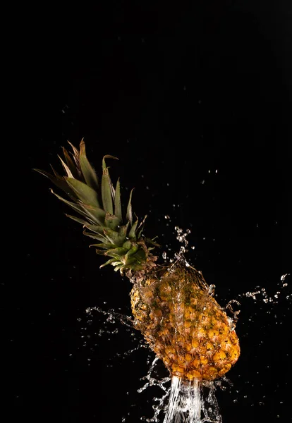 Pineapple with beautiful splash of water with black background and selective focus.