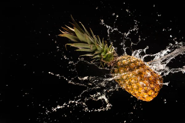 Pineapple with beautiful splash of water with black background and selective focus.
