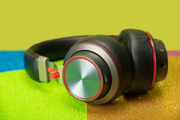 Headphone of neutral color, placed on a colored surface, selective focus.