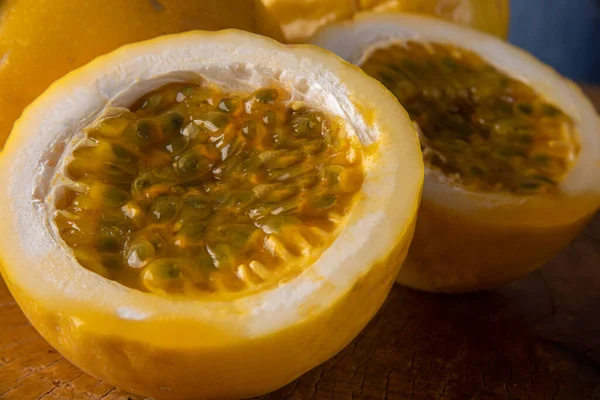 Passion fruit, maracuja, being squeezed into a glass on rustic wood, blue background, selective focus.