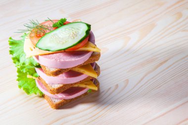 Sosisli ve peynirli sandviç, otlar, domates ve salatalık, üçgen şeklinde koyu bir tabakta. Öğlen bir şeyler atıştır. Seninle bir sandviç. Kahvaltı ya da öğle yemeği için kadeh kaldıralım.