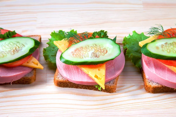 Sosisli ve peynirli sandviç, otlar, domates ve salatalık, üçgen şeklinde koyu bir tabakta. Öğlen bir şeyler atıştır. Seninle bir sandviç. Kahvaltı ya da öğle yemeği için kadeh kaldıralım.