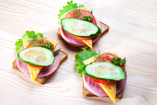 Sosisli ve peynirli sandviç, otlar, domates ve salatalık, üçgen şeklinde koyu bir tabakta. Öğlen bir şeyler atıştır. Seninle bir sandviç. Kahvaltı ya da öğle yemeği için kadeh kaldıralım.