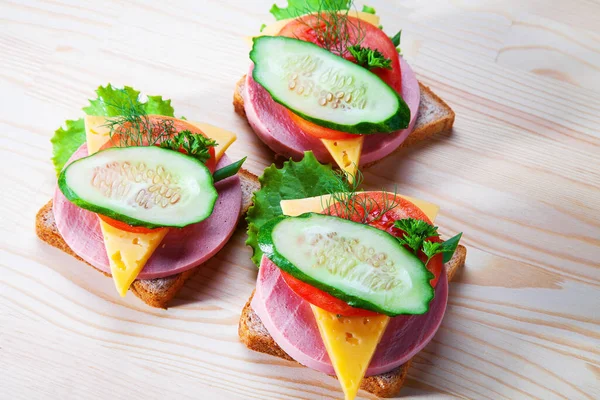 Sosisli ve peynirli sandviç, otlar, domates ve salatalık, üçgen şeklinde koyu bir tabakta. Öğlen bir şeyler atıştır. Seninle bir sandviç. Kahvaltı ya da öğle yemeği için kadeh kaldıralım.