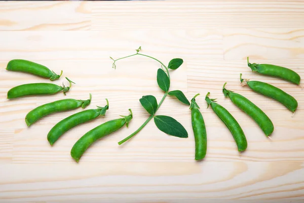 Kabuklardaki yeşil bezelyeler ahşap bir arka planda yatıyor. Sağlıklı yeşil sebzeler. Mesaj için yer. Ahşap bir masada duran lezzetli olgun bezelyeler. Kırsal ahşap arka planda yeşil bezelye, fotokopi alanı, doğal ahşap masa. Düz yatıyordu.