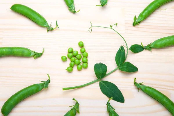Kabuklardaki yeşil bezelyeler ahşap bir arka planda yatıyor. Sağlıklı yeşil sebzeler. Mesaj için yer. Ahşap bir masada duran lezzetli olgun bezelyeler. Kırsal ahşap arka planda yeşil bezelye, fotokopi alanı, doğal ahşap masa. Düz yatıyordu.