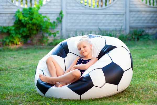 6-7 yaşlarında güzel bir kız gün batımında bahçede dinleniyor. Bahçede dinlenme ve meditasyon, tatilde. Mutlu bir çocukluk, yaz tatilleri, çocuklarla kendi bahçelerinde karantina altında geçirilen yaz tatilleri.