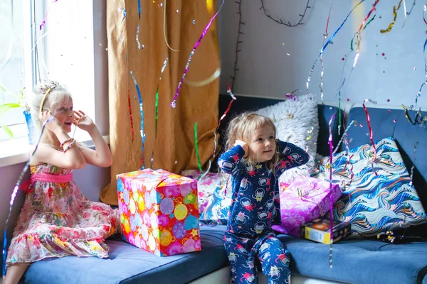 Evde Çocuk Günü sabahı doğumu. Çocuklar kanepede oturuyorlar ve çok renkli konfeti parçaları tepeden tırnağa uçuyor. Mutlu Yıllar Aile Kutlaması