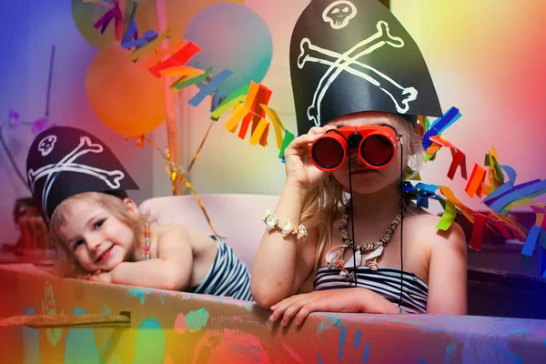 İki komik çocuk evdeki karton bir deniz gemisinde korsan kostümü giyip oynuyorlar..