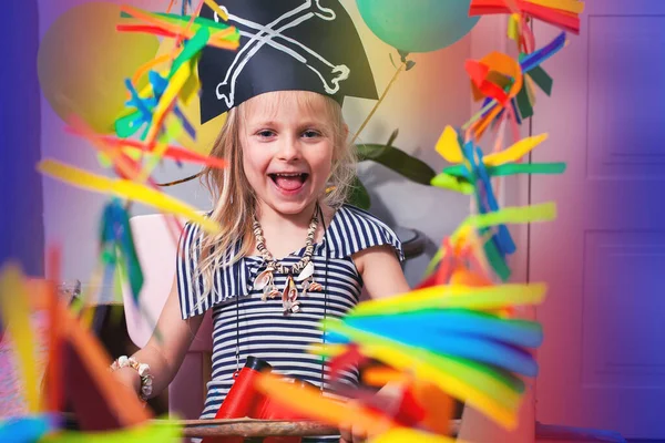 A child in a pirate costume smiles and plays. Bright festive photo of a pirate party. Baby's birthday. Adventure and travel at home