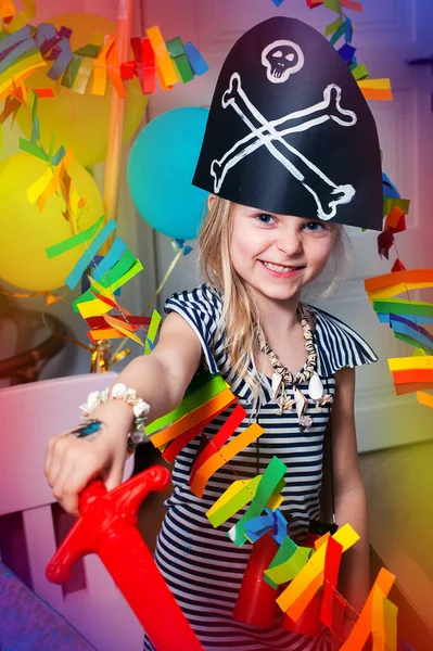 Korsan kostümlü bir çocuk gülümseyip oynuyor. Korsan partisinin neşeli fotoğrafı. Bebeğin doğum günü. Macera ve evde seyahat