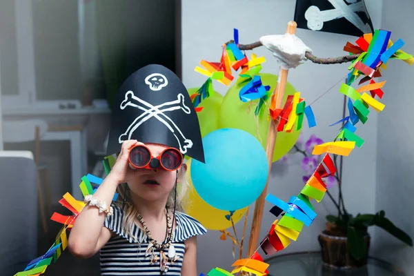 Korsan kostümü giymiş neşeli küçük bir çocuk, elinde siyah bayrakla karton bir deniz gemisinde oynuyor. Aileyle evde eğlenceli oyunlar. Evdeki seyahatler ve maceralar