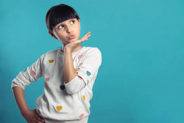 Kız yana bakıyor ve mavi arka planda bir öpücük yolluyor.