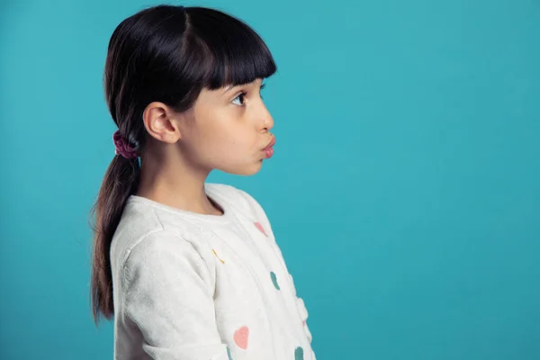 Mavi arka planda profilde güzel bir kızın portresi.