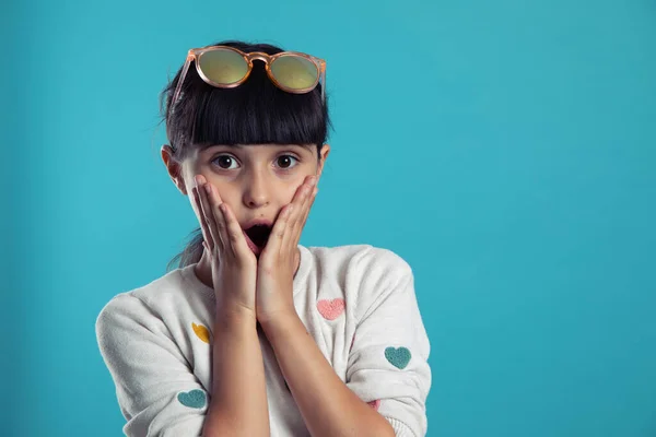 Mavi arka planda güzel, şaşkın bir kızın portresi