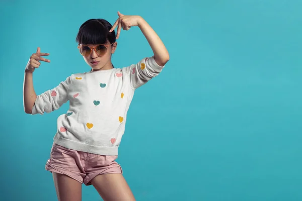 Eğlenceli kız mavi arka planda güneş gözlüğü takıyor.