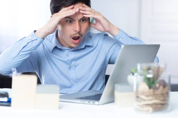Bilgisayarında gördüklerine inanmayan ve ofisinde çalışan bir adam.
