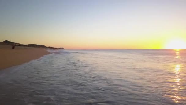 メキシコのカボ・サン・ルーカスの海と砂浜に沈む夕日のダイナミックな空中ビュー — ストック動画